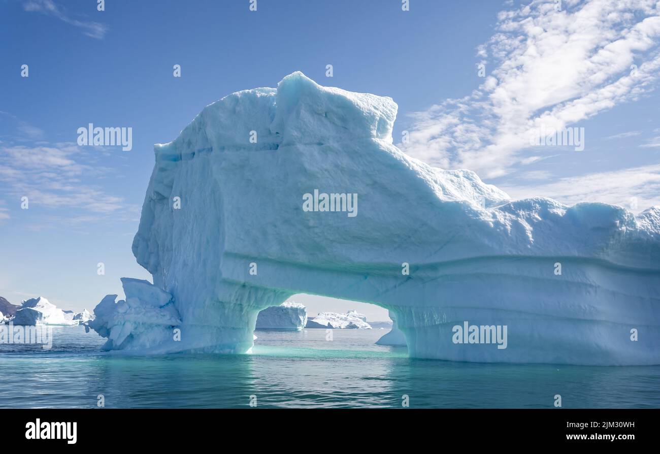 Massive iceberg with arch and beautiful aquamarine coloured ice and sea in Disko Bay, Greenland Stock Photo