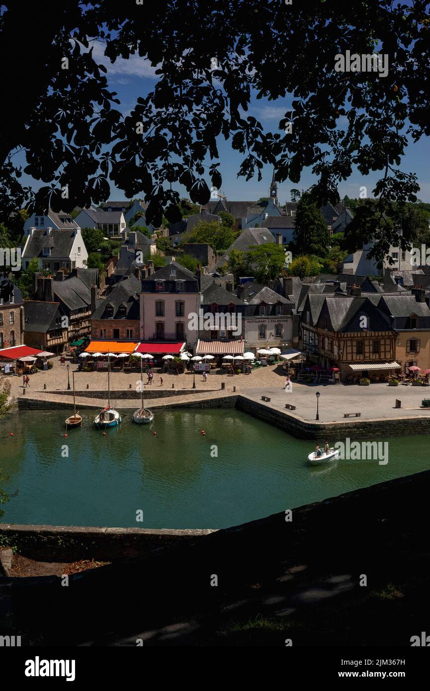 Vista from the Promenade du Loch belvedere over the green waters of the River Loch of Place Saint-Sauveur and the Saint-Goustan quayside at Auray, Morbihan, southern Brittany, France.  Saint-Goustan, once a busy fishing and trading port, is now a popular tourist area with restored ancient buildings housing restaurants, creperies, bars and pavement cafes offering dining under colourful awnings and sun umbrellas. Stock Photo