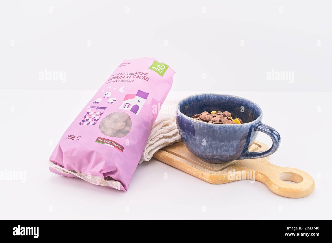 organic farming cocoa corn and rice flakes with bowl, cutting board and kitchen cloth on a white table Stock Photo