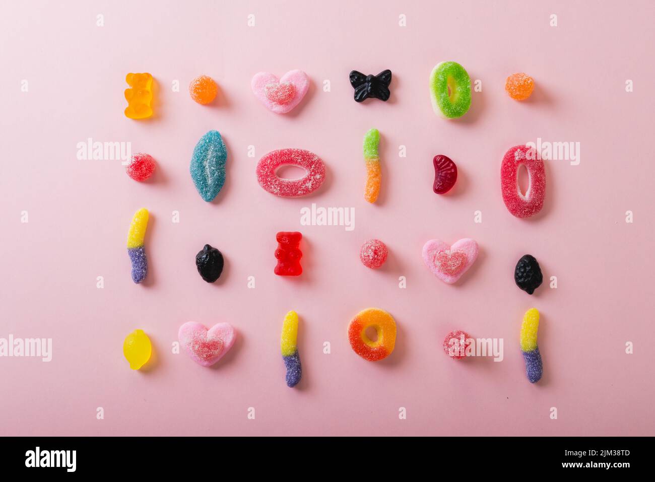 Directly above view of differently shaped multi colored sugar candies arranged on pink background. unaltered, unhealthy eating and sweet food concept. Stock Photo