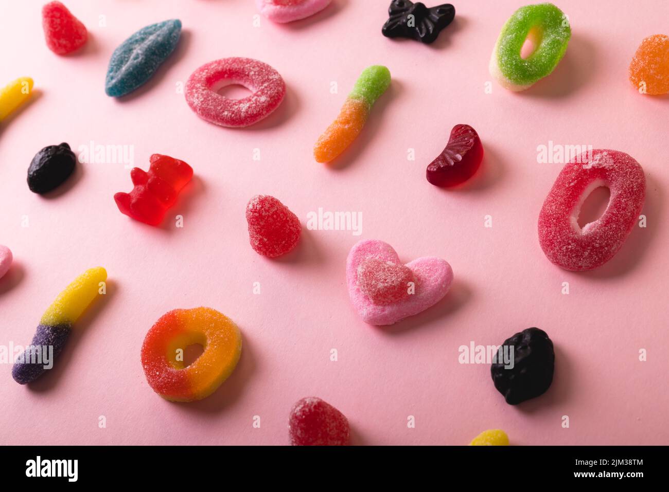 High angle full frame view of multi colored differently shaped sugar candies on pink background Stock Photo