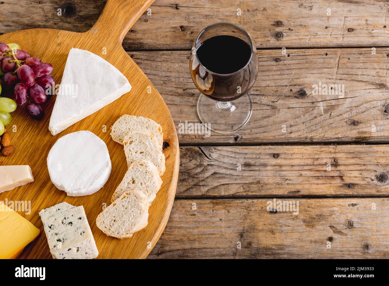 Overhead view of various cheese with grapes and red wine on wooden table, copy space. unaltered, food, fruit, drink, alcohol and dairy product. Stock Photo
