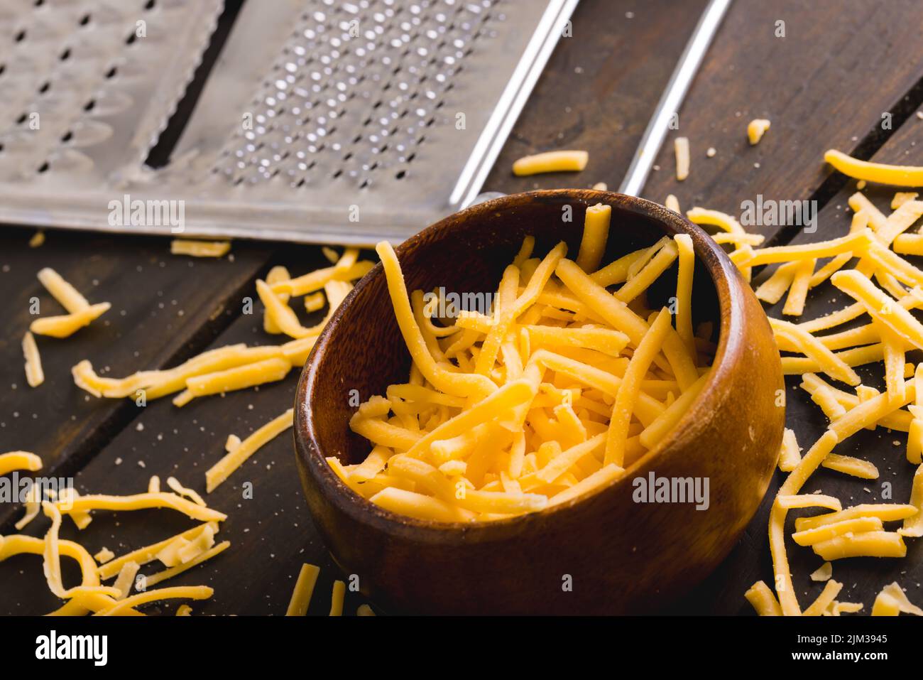 https://c8.alamy.com/comp/2JM3945/close-up-of-grated-yellow-cheese-and-bowl-by-grater-on-table-copy-space-2JM3945.jpg