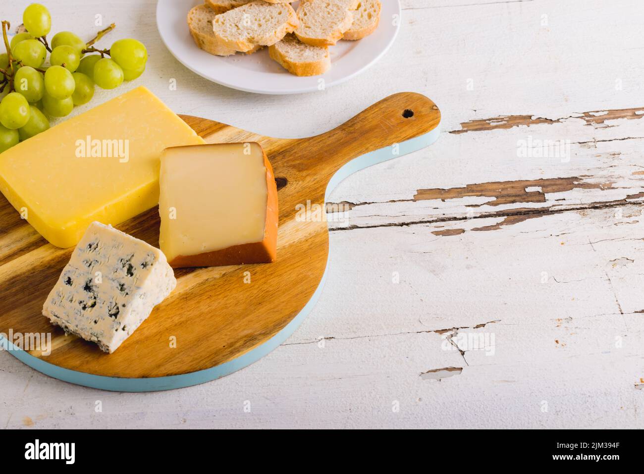 High angle view of various cheese with grapes on wooden board, copy space. unaltered, food, fruit and dairy product. Stock Photo
