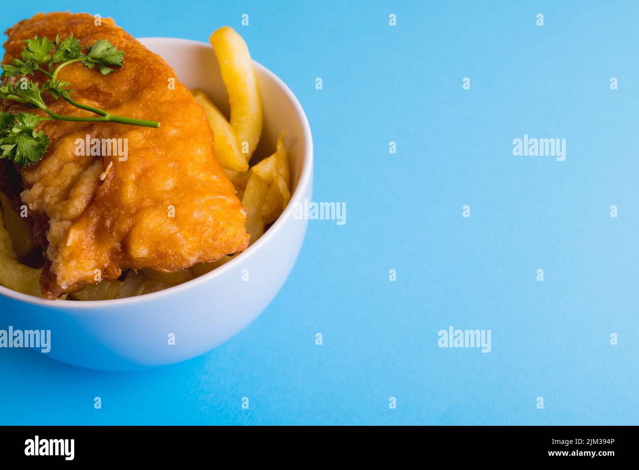 Close-up of french fries with seafood in bowl on blue background, copy space. unaltered, food, fried food, ready-to-eat, studio shot and meal. Stock Photo