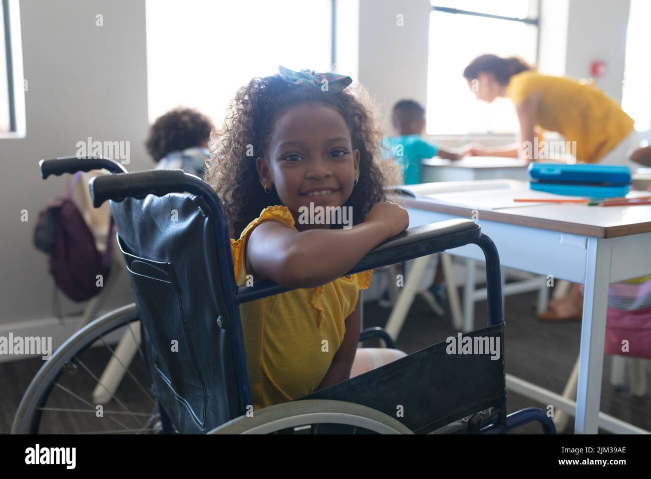 Portrait of smiling african american elementary girl sitting on ...