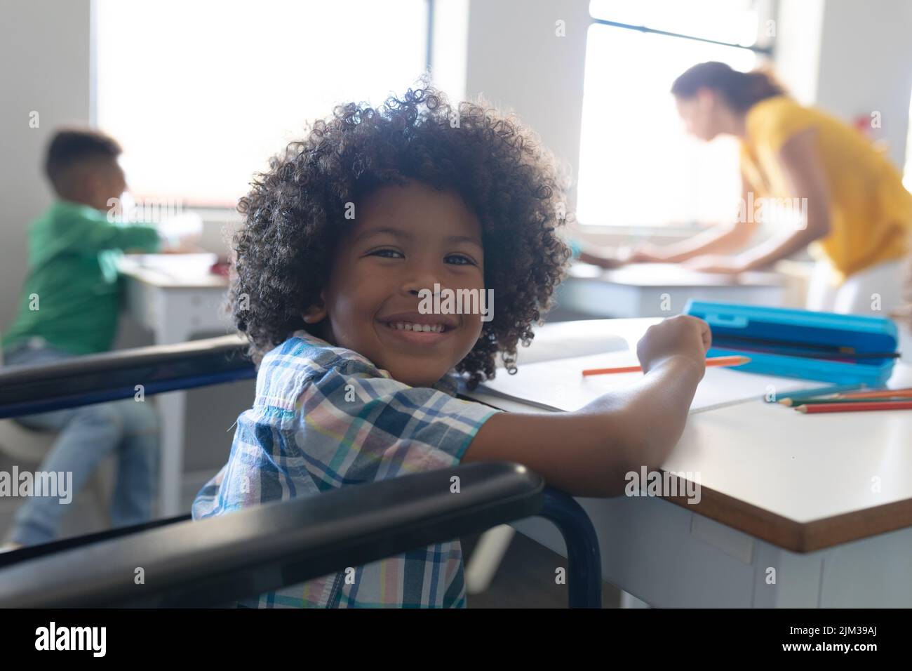 Portrait of smiling african american elementary boy sitting on ...