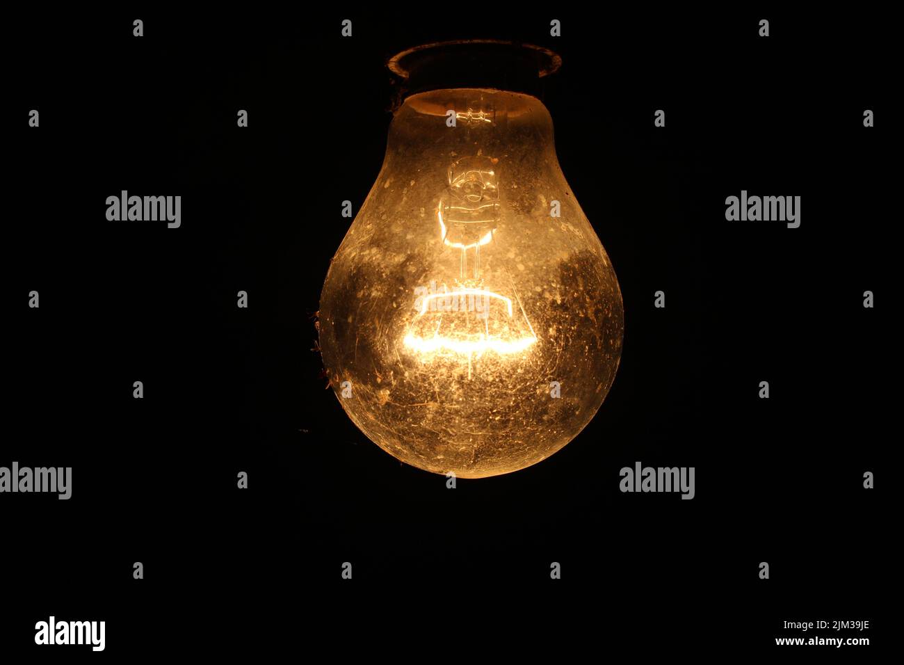 Tungsten light bulb lit on black background... Stock Photo