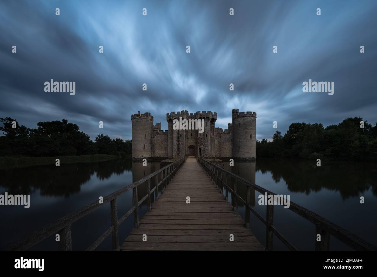 Long exposure image of Bodiam Castle in East Sussex at sunset with the castle and trees reflected in the surrounding moat Stock Photo
