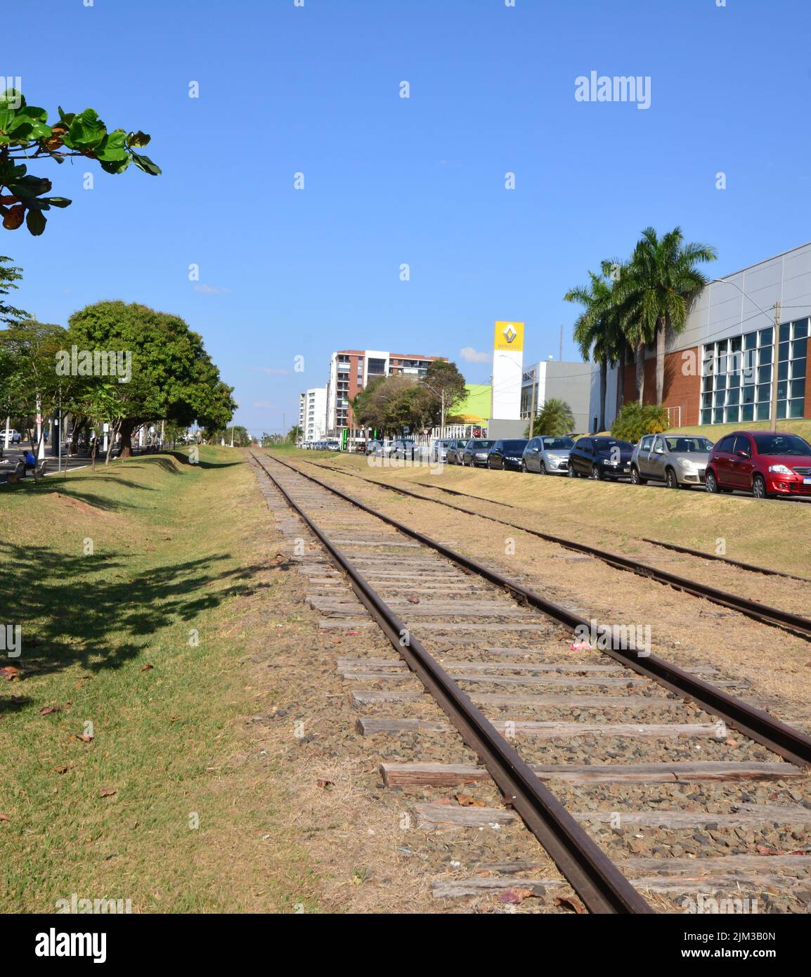 Railroad in urban area, vehicle parking, trees, and buildings in the background, highlighting the logo of a large French automaker, Brazil, South Amer Stock Photo