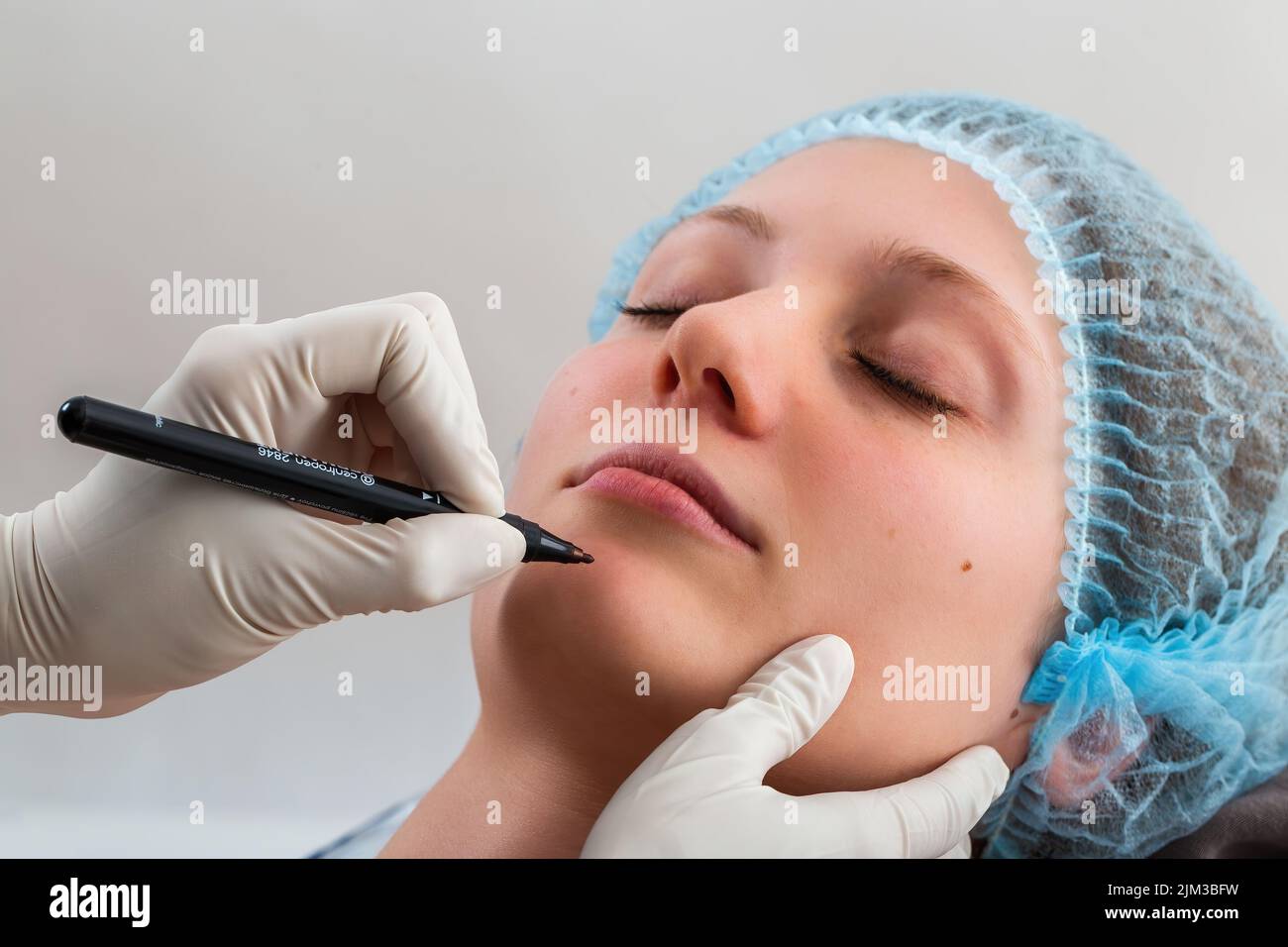 Dotor in gloves preparing young female for cosmetic surgery Stock Photo