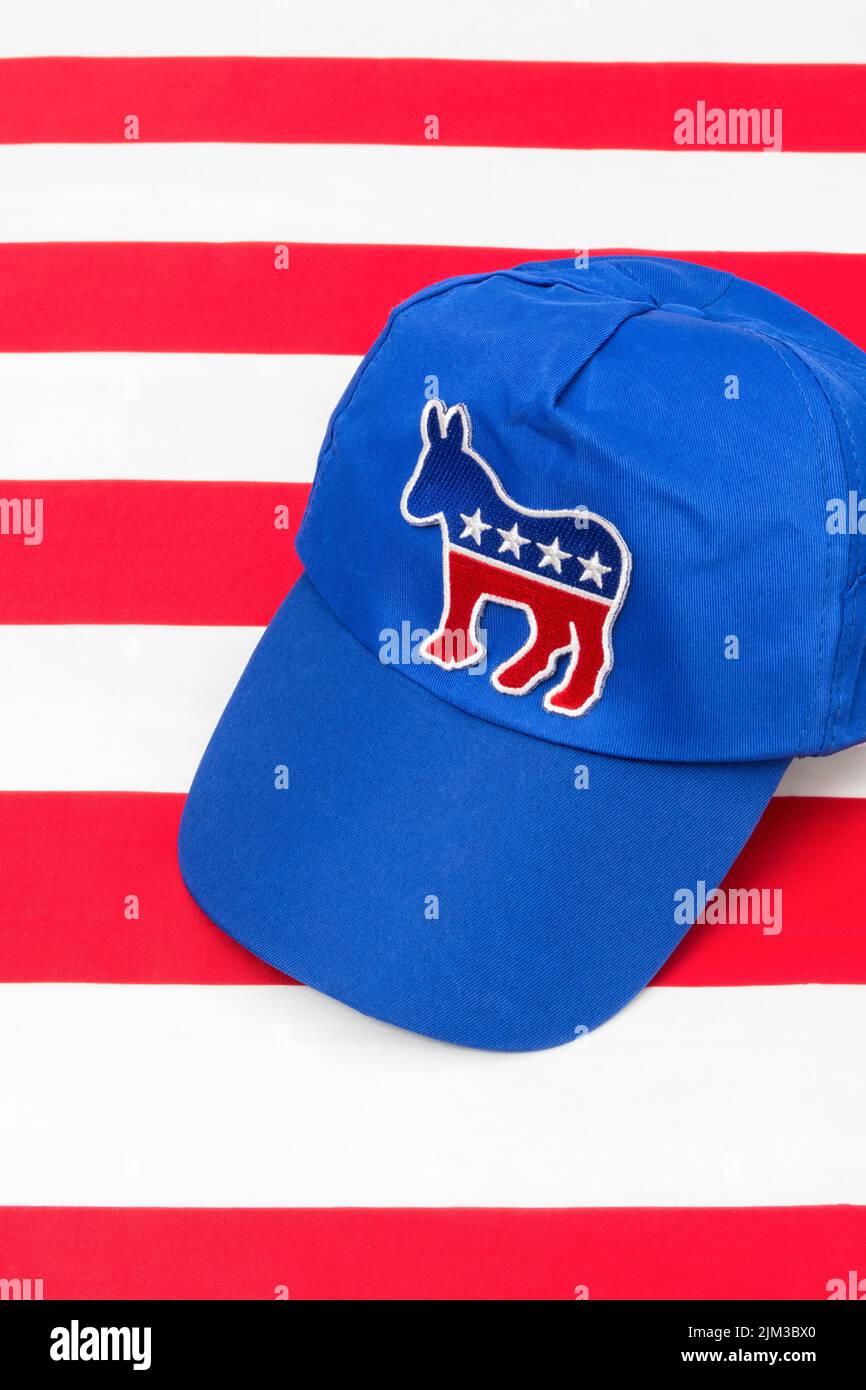 Blue DNC cap with Dem donkey badge & US Stars and Stripes flag. For 2024 US Presidential election & Republican Red Wave wipe-out of Democrats. Stock Photo