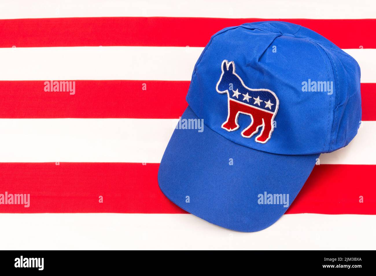 Blue DNC cap with Dem donkey badge & US Stars and Stripes flag. For 2024 US Presidential election & Republican Red Wave wipe-out of Democrats. Stock Photo