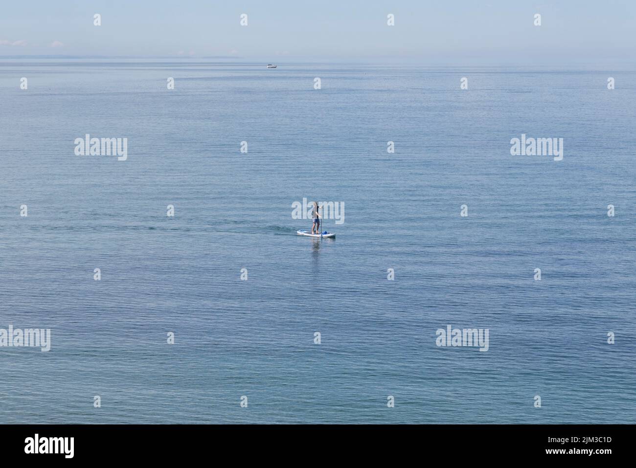 A man paddle boarding in the sea. Health, fitness, holiday, recreation, time alone concept. Stock Photo