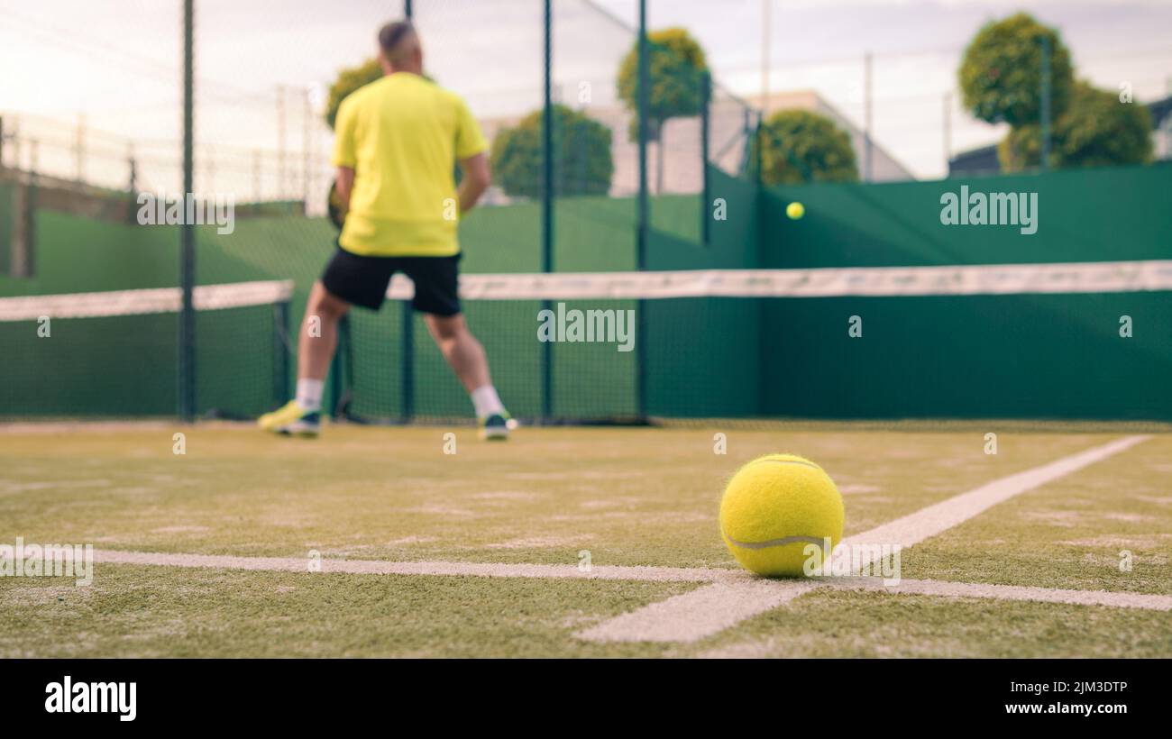 Monitor practicing paddle sport on the outdoor court. Man teaching padel class to his student. Professional people trainer how to play paddel. Learn a Stock Photo