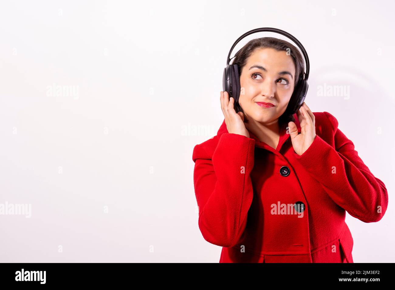 Girl with red coat and headphones listening to music. white background Stock Photo
