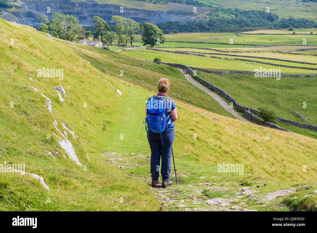 Woman carrying a blue rucksack is admiring the view above the Ingleton waterfalls walk Stock Photo