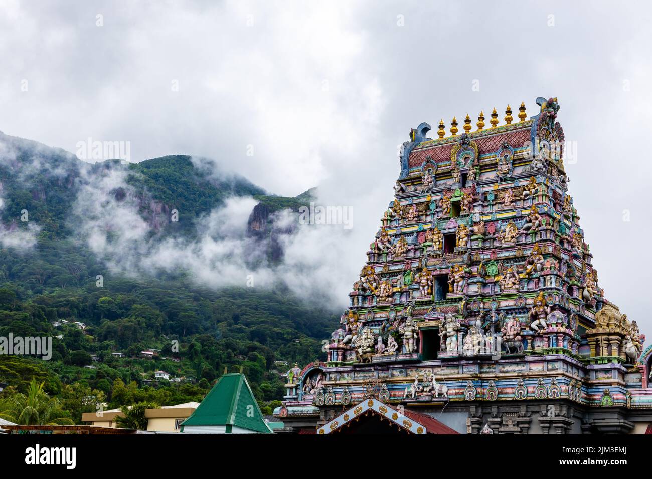 Arul Mihu Navasakthi Vinayagar Temple with colorful traditional Hindu gods and deities sculptures and tropical mountains in clouds in the background Stock Photo