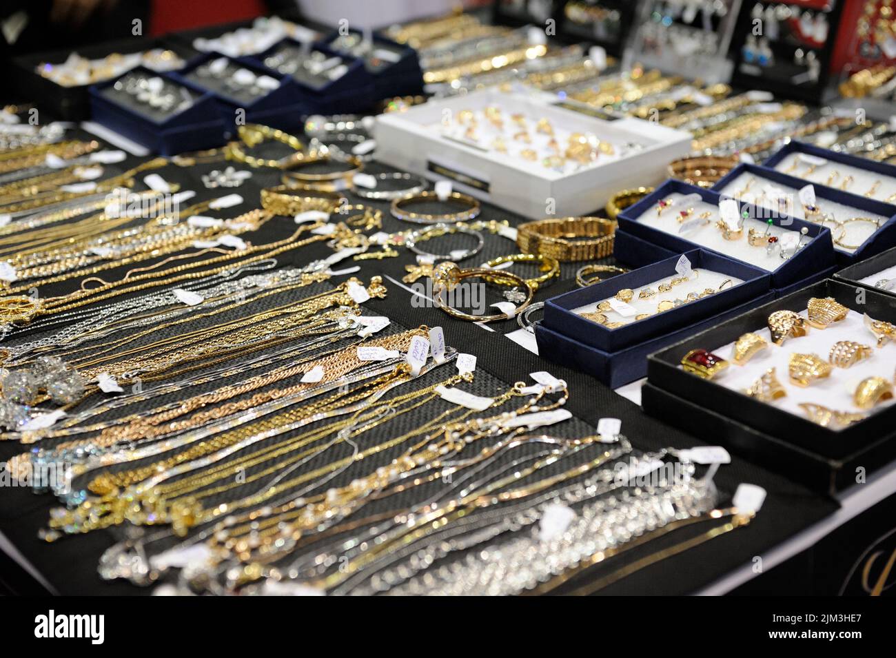 A variety of golden jewels under a glass display at a market Stock Photo