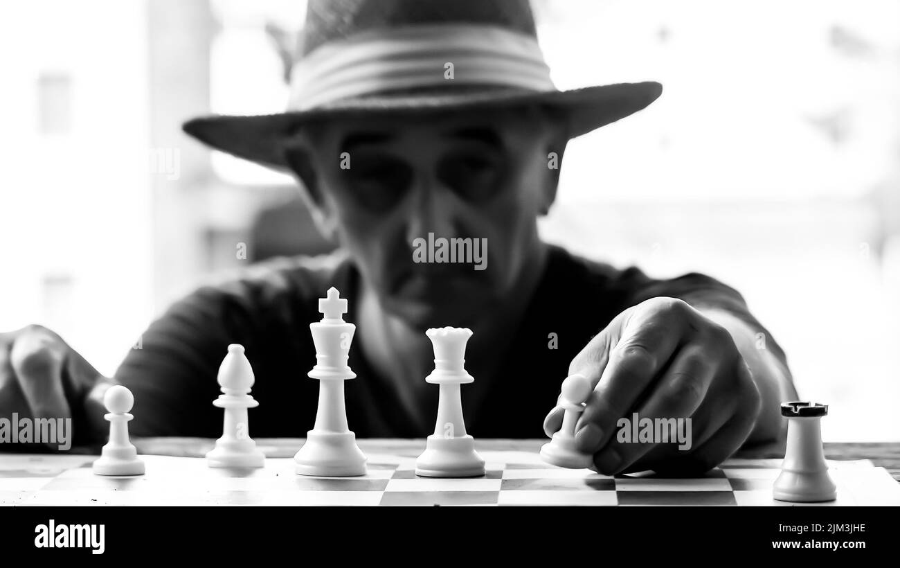 Man is playing chess with hat on head Stock Photo