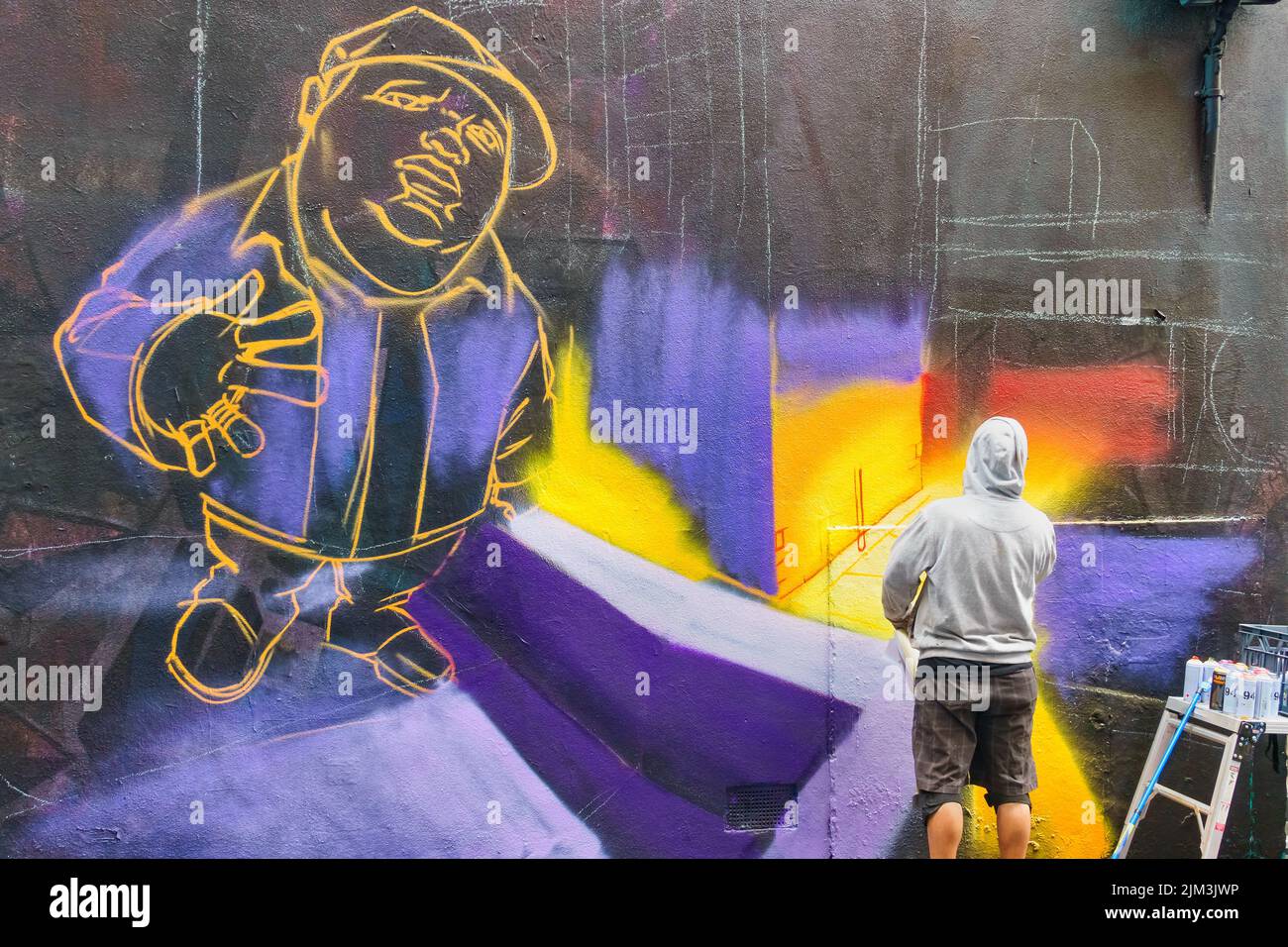 Street artist works on a mural at the famous Hosier Lane in downtown Melbourne, Victoria, Australia. Stock Photo