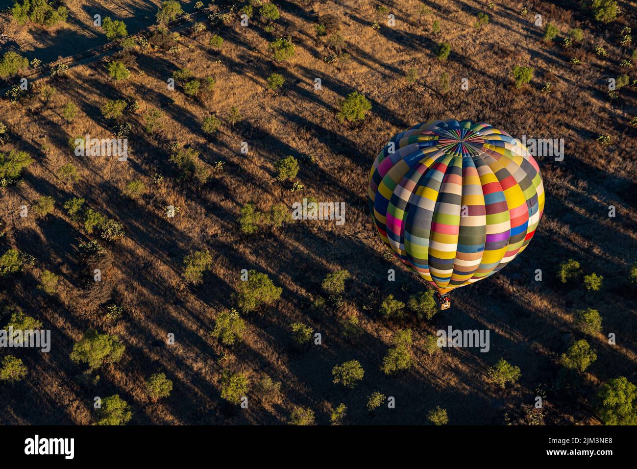 An aerial shot of a colorful hot air balloon flying over desert with ...