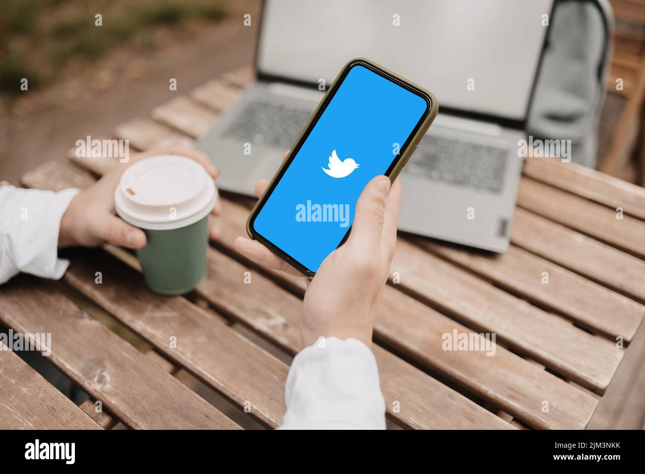 A hand with coffee and a phone with Twitter social network Stock Photo
