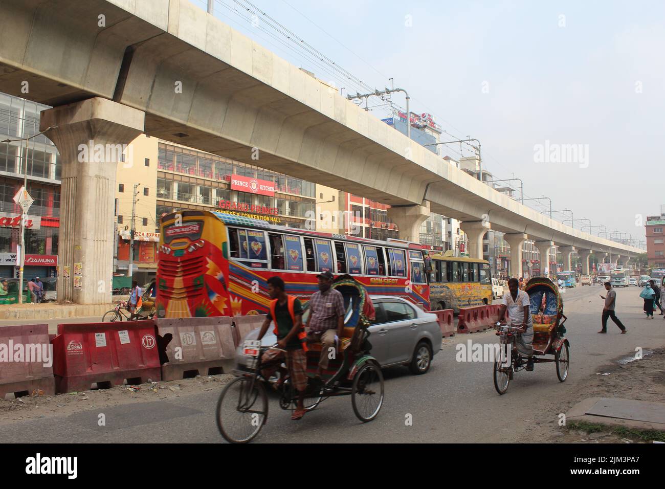 The people in cycle rickshaws and the Metro Rail in Mirpur, Dhaka, Bangladesh Stock Photo