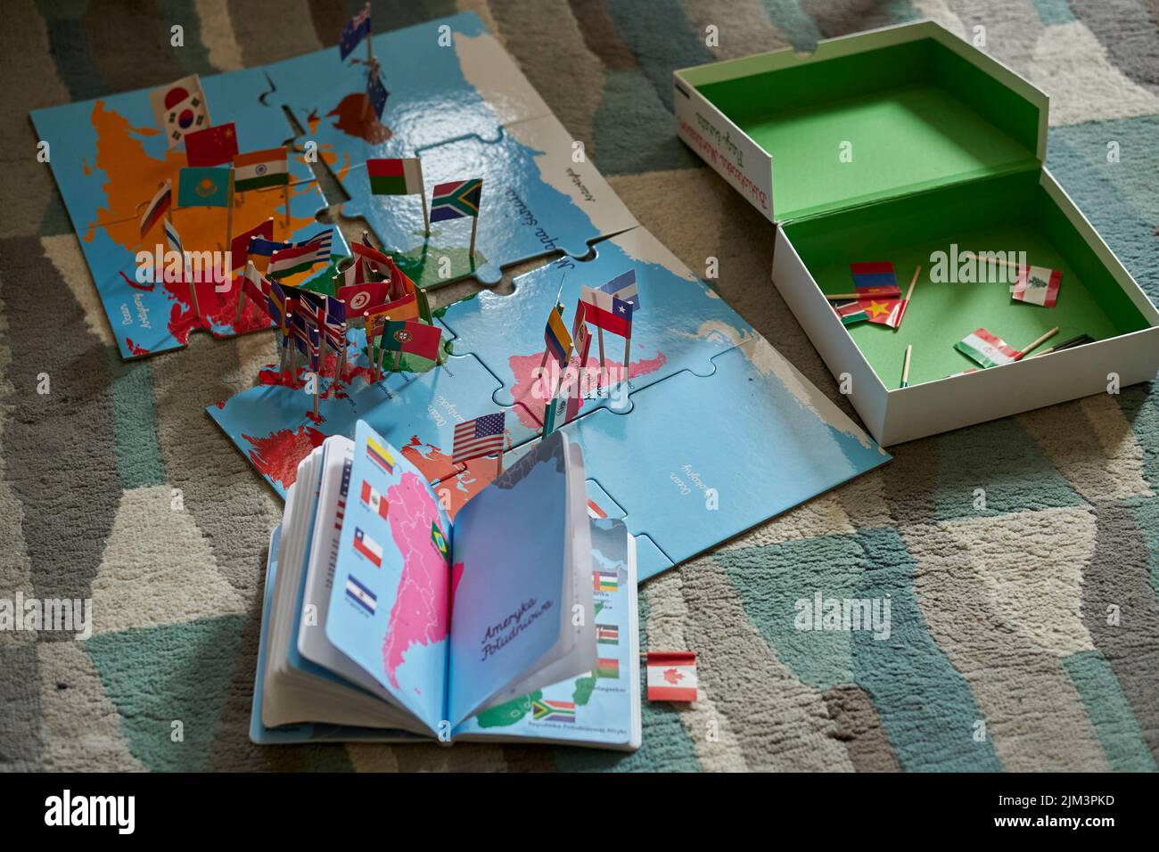 An open book and puzzle about the world and flags on a floor. Poznan,Poland Stock Photo