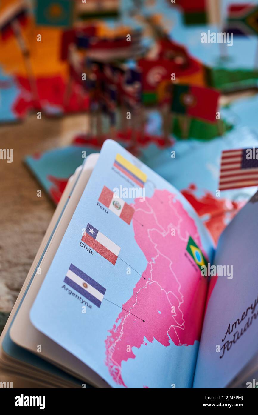 An open book and puzzle about the world and flags on a floor. Poznan, Poland Stock Photo