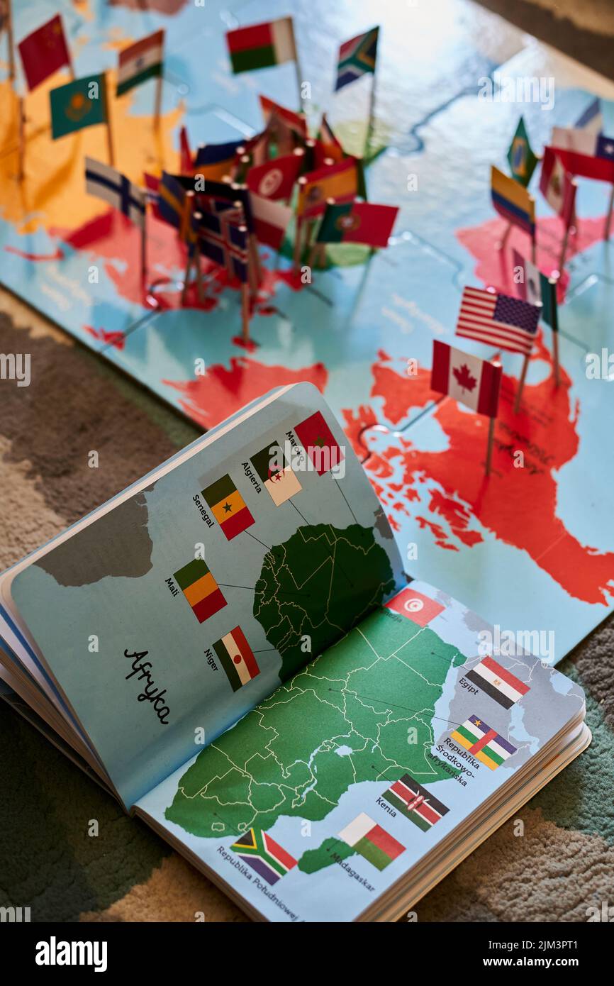 An open book and puzzle about the world and flags on a floor. Poznan,Poland Stock Photo