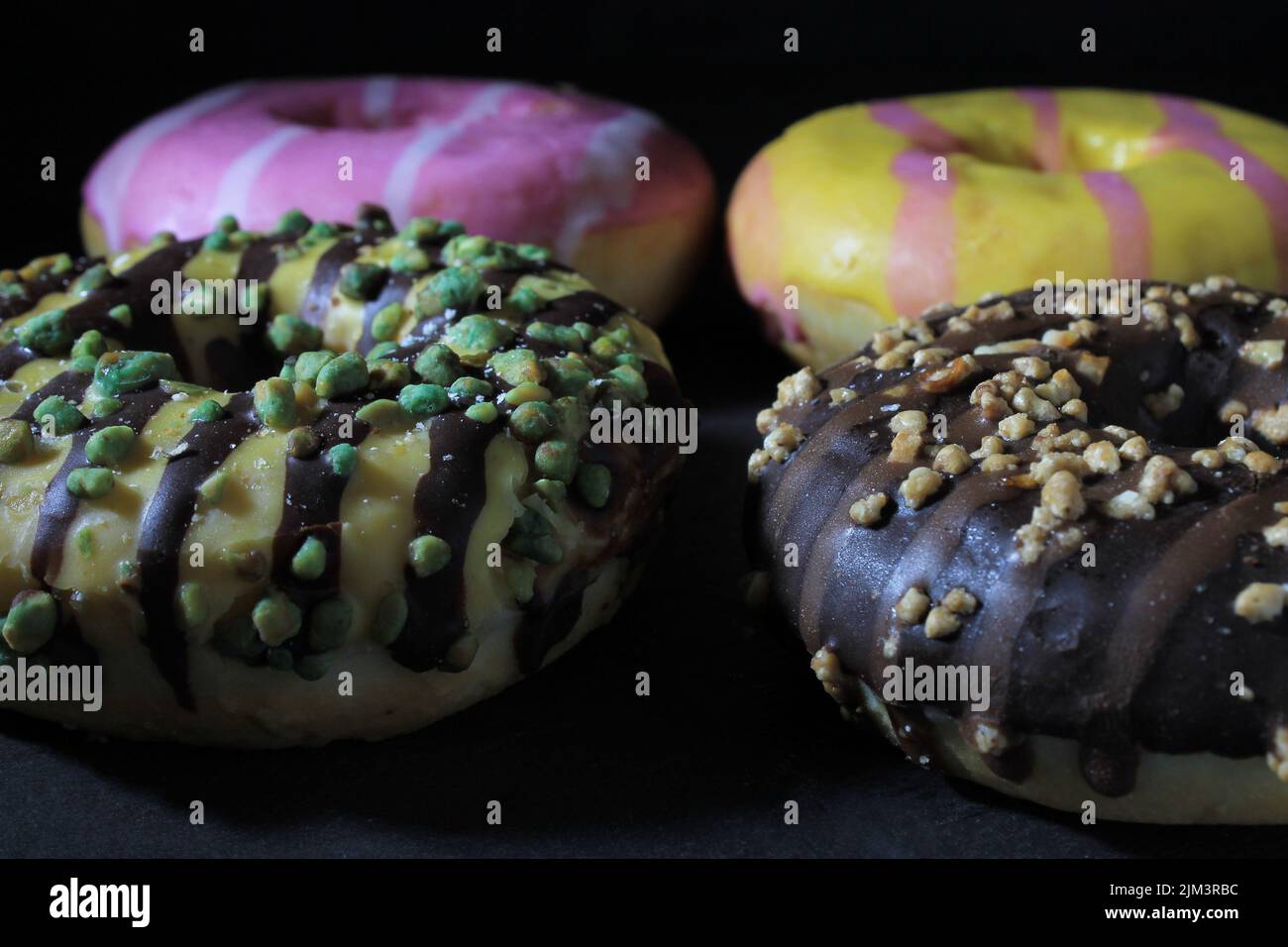 Donut Rbcs closeup of several colorful donuts on a table, with dark background ...