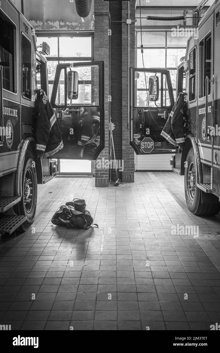 A grayscale shot of two fire engine and ladder trucks sit in the