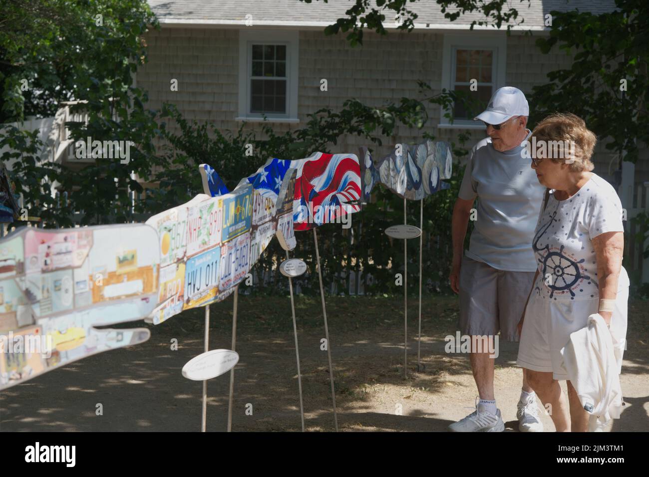 a couple tours the whale cutout display at Chatham 'Art in the Park' project on Cape Cod, USA Stock Photo