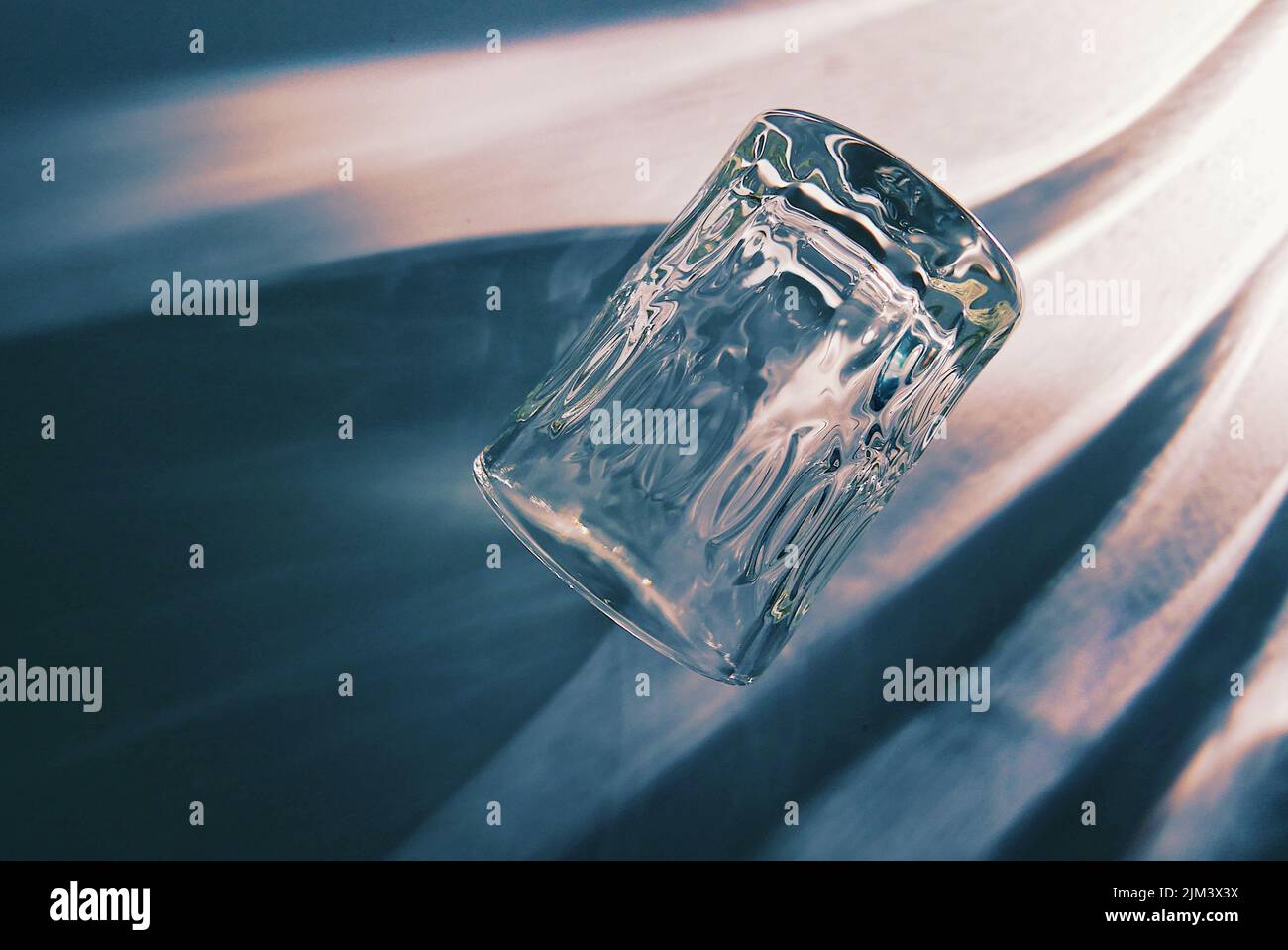 A closeup shot of glass lying on its side with shadow in blue ...