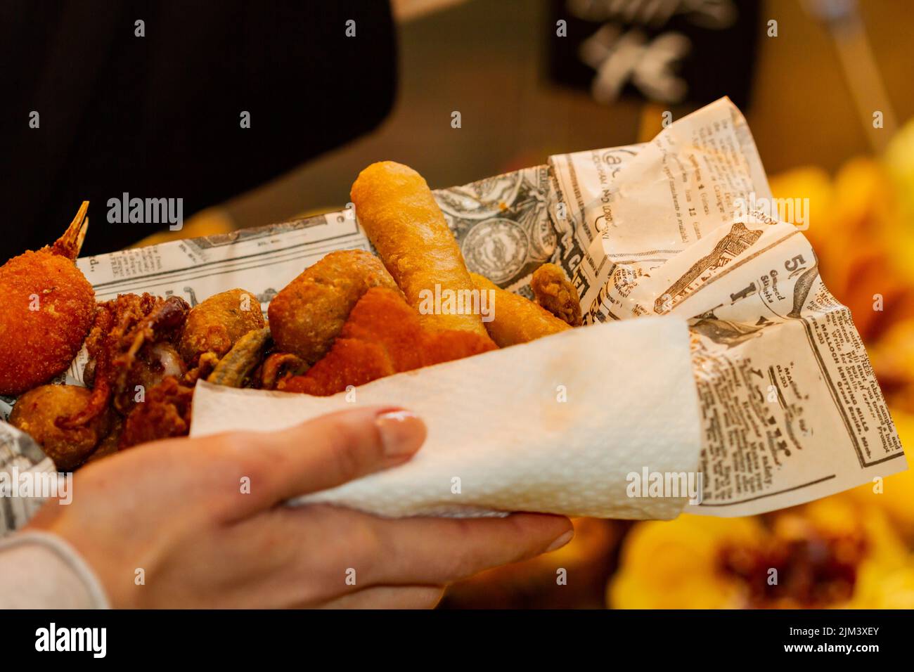 Unrecognizable woman's hand holding fried and breaded fish and seafood ...