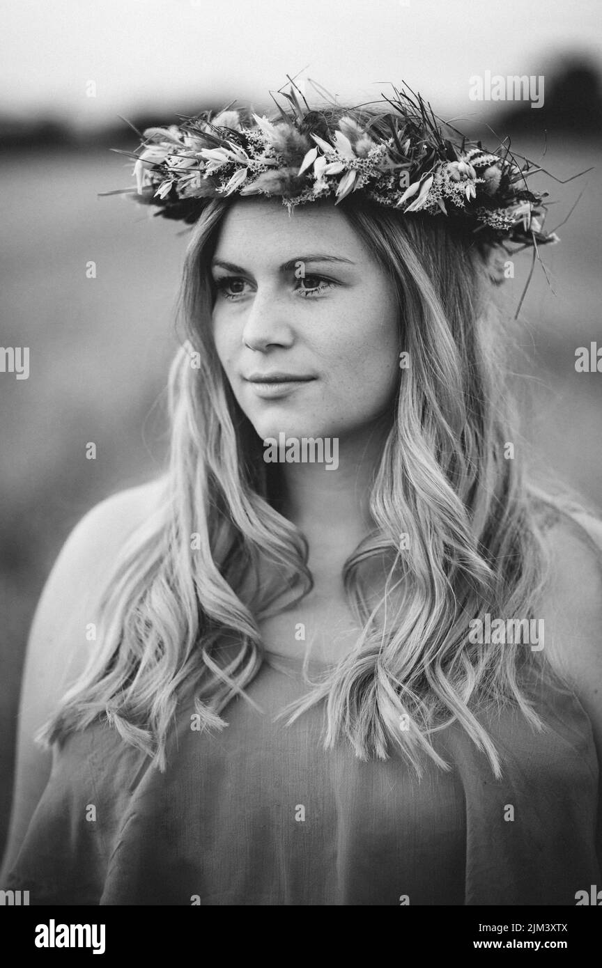 A vertical grayscale shot of a beautiful young female posing in a headdress Stock Photo