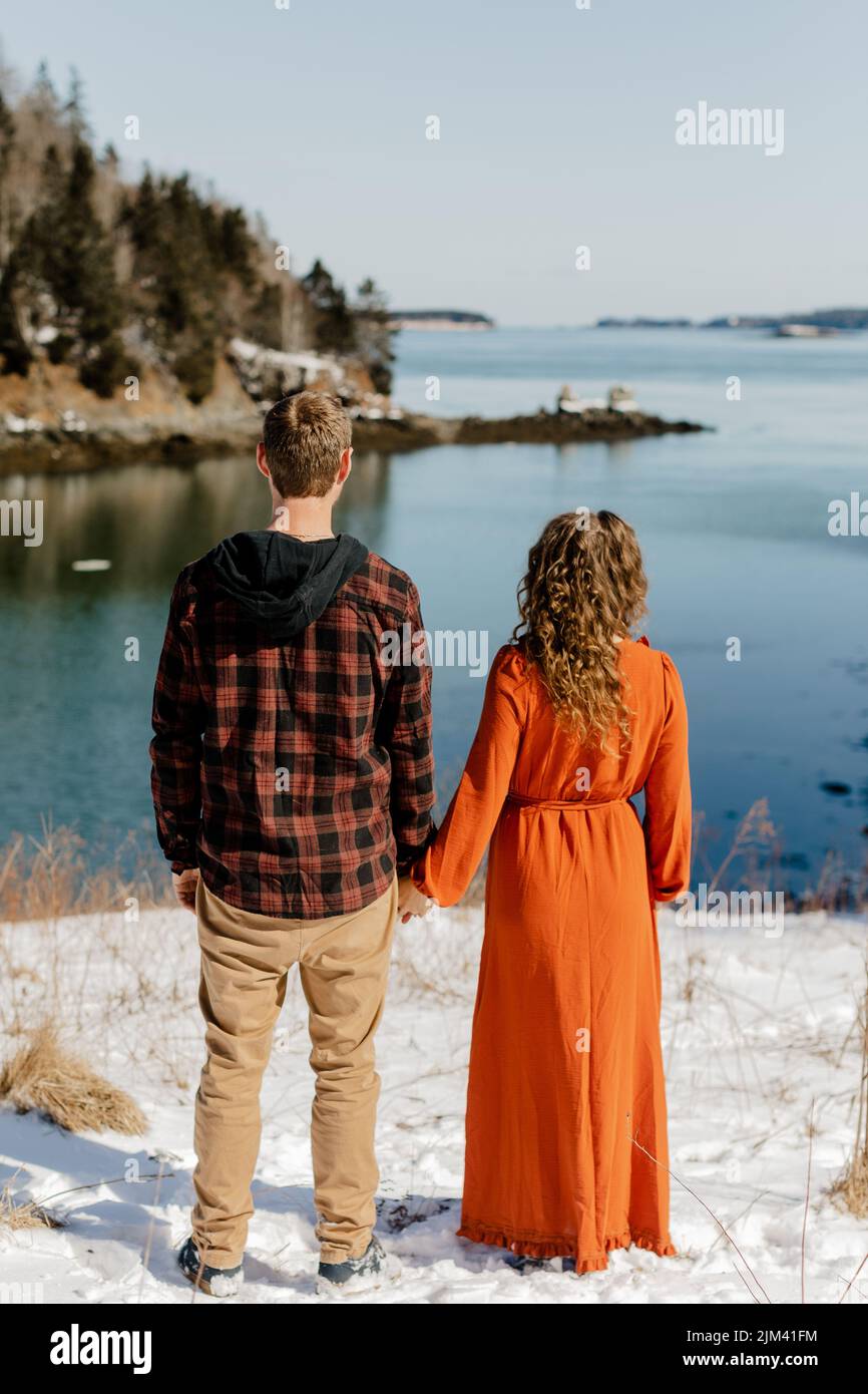 A backshot of a couple standing on the snowy ground on the Deer Island  along a river on a sunny in New Brunswick, Canada Stock Photo - Alamy