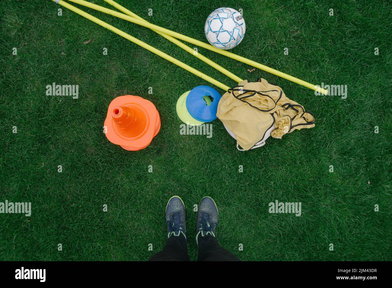 A top view of a person's feet with football game equipment on the grass