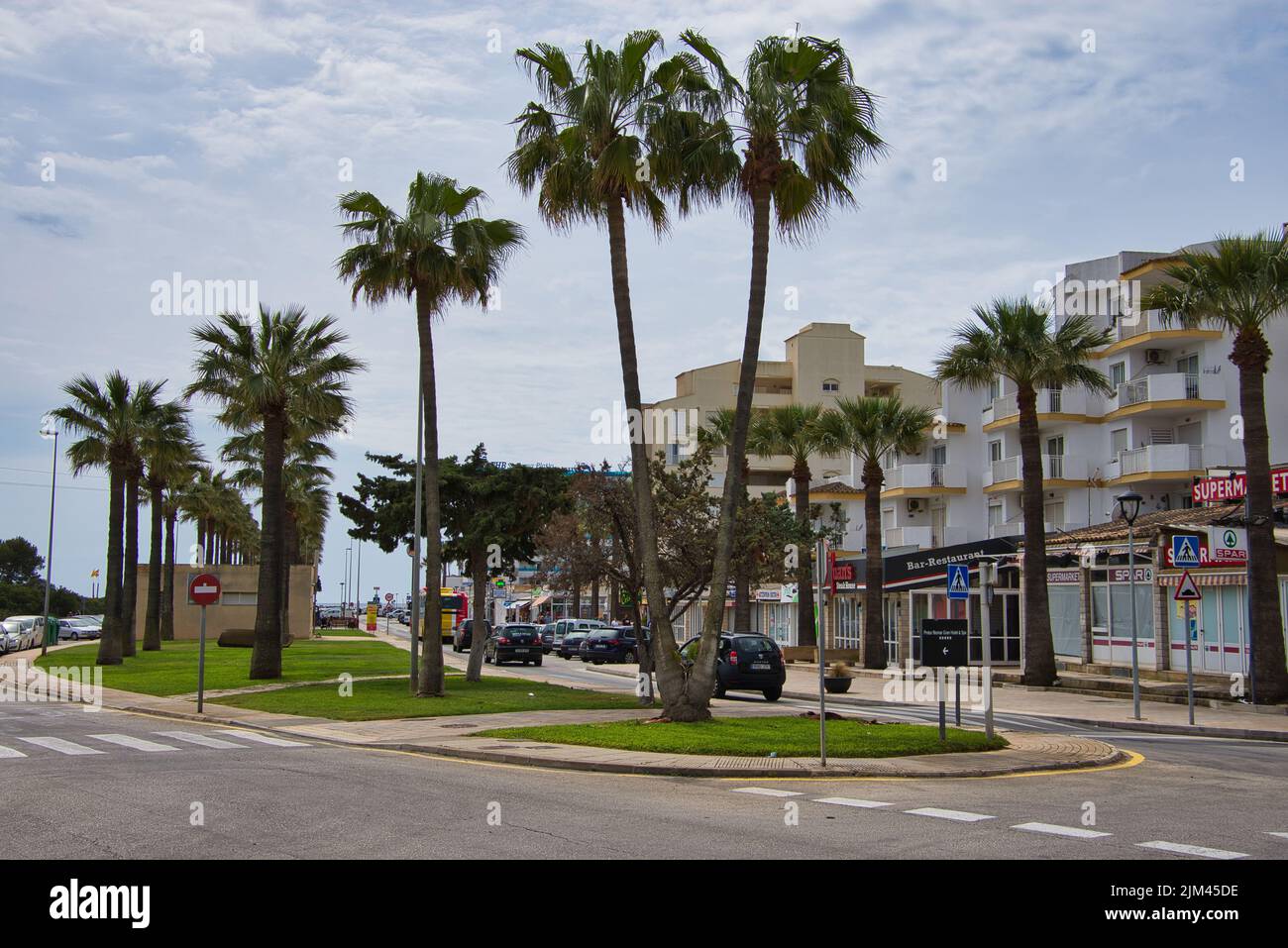 Picture shows a street in Sa Coma, Mallorca with palm trees, a supermarket and cars Stock Photo