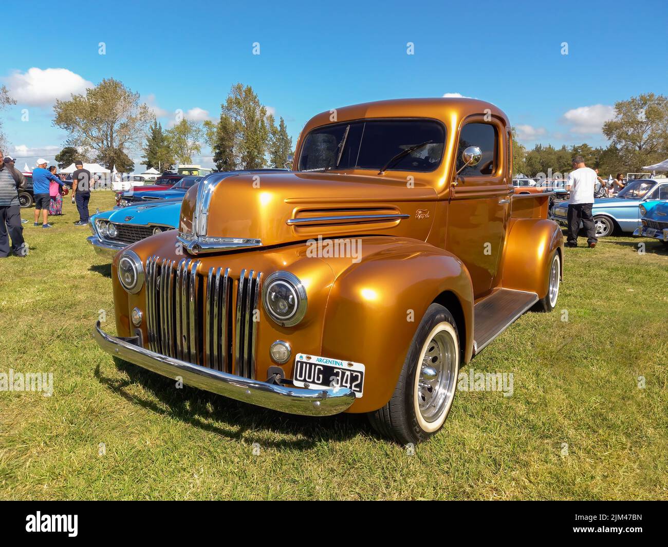 Old golden utility Ford pickup truck 1942 - 1947 in the countryside. Nature grass trees. Classic car show. Copyspace Stock Photo