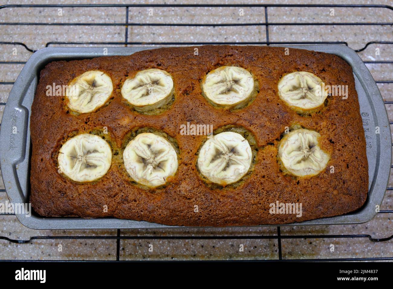 A top view of a freshly baked banana bread in a baking pan on a cooling