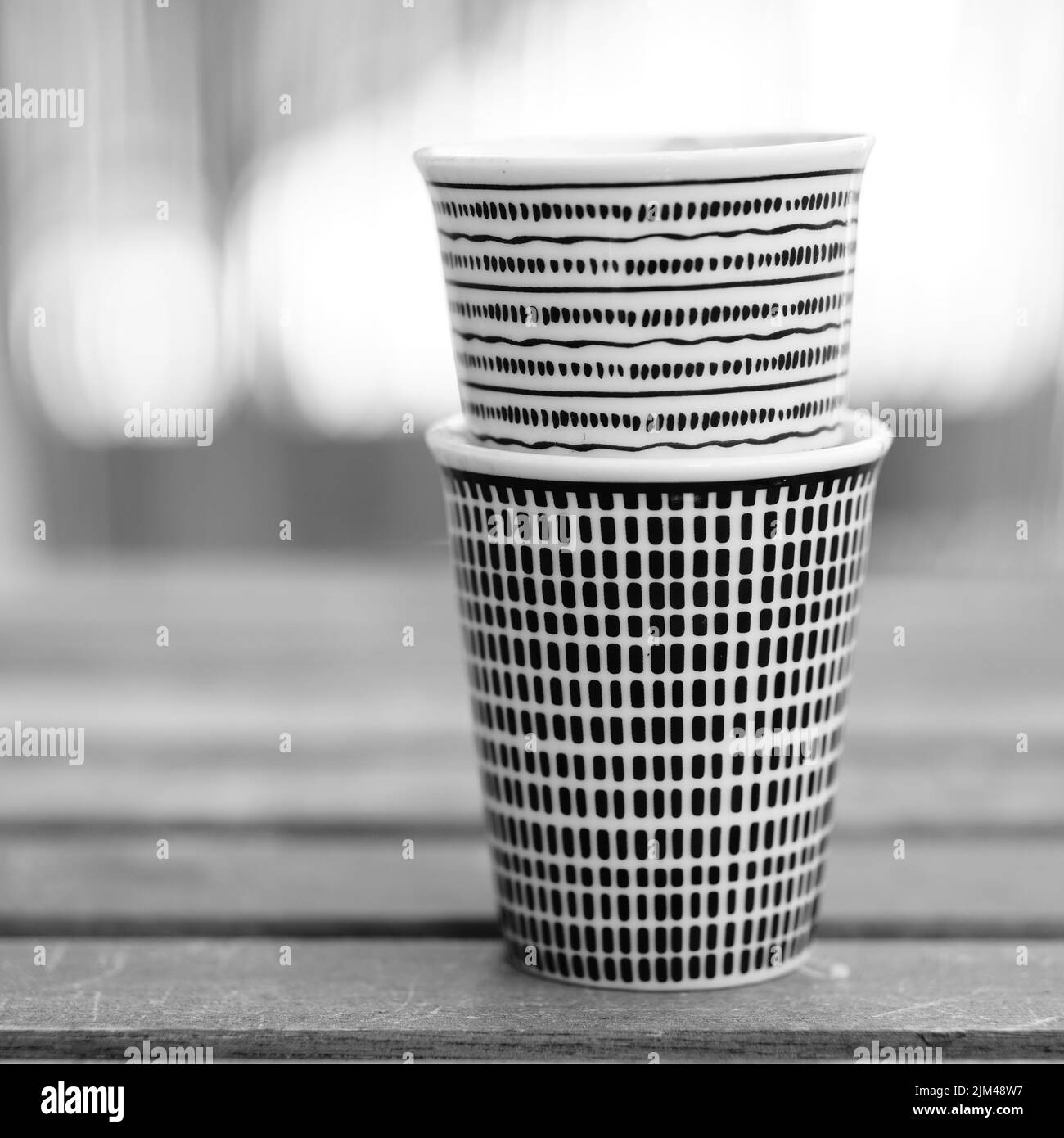 A vertical grayscale closeup of paper espresso cups on the bench Stock