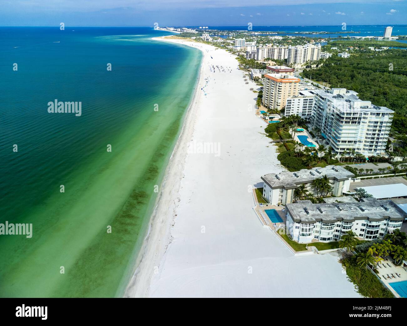 An aerial view of green water and modern buildings in Lido Key ...