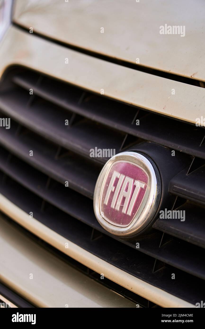 A vertical closeup shot of a Fiat logo on a parked car Stock Photo