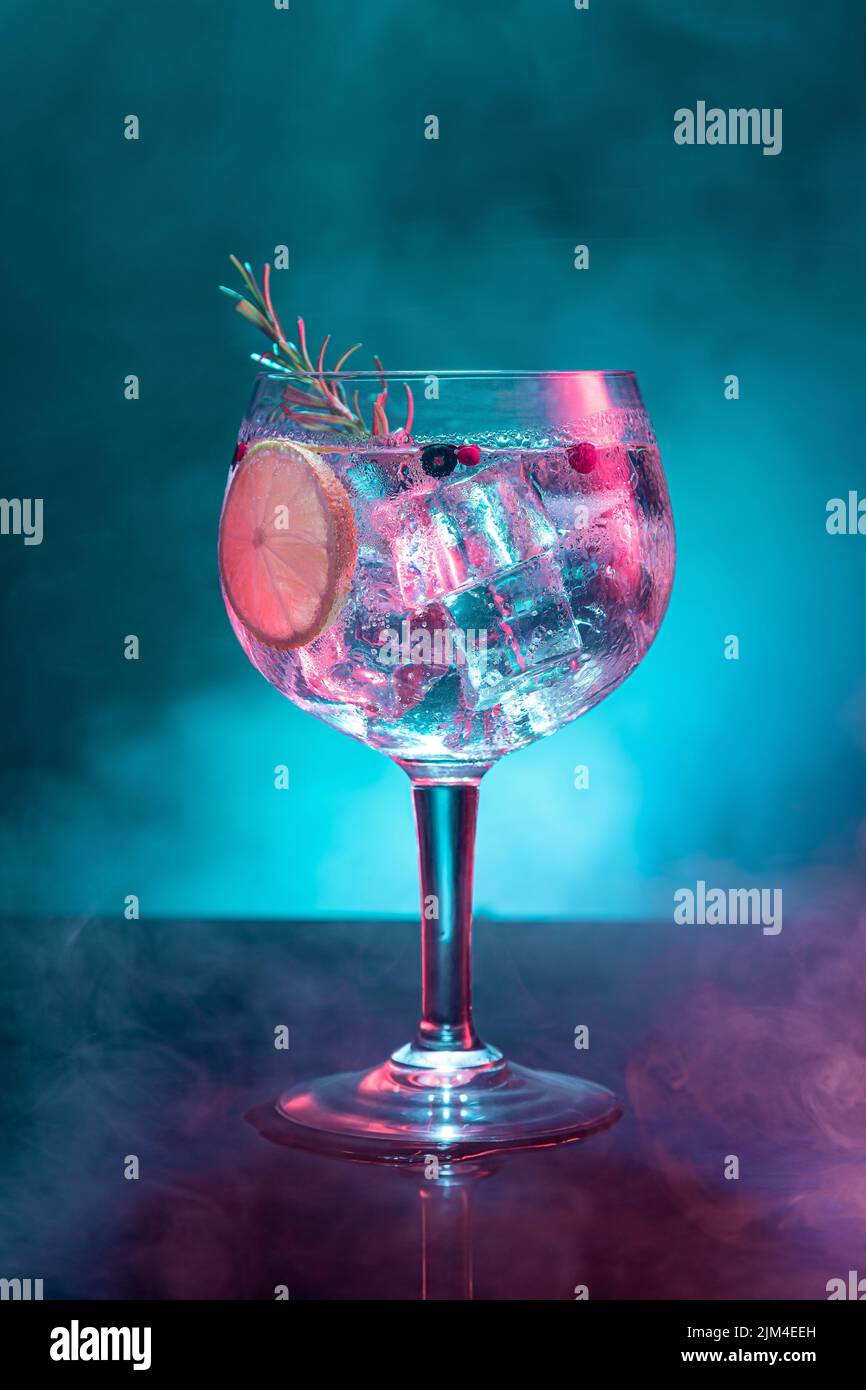 Cold gin and tonic under pink and blue light illumination on smoky