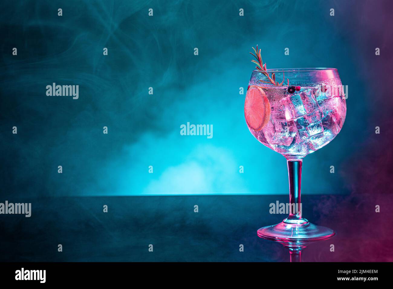 Cold gin tonic under pink and blue light illumination on smoky