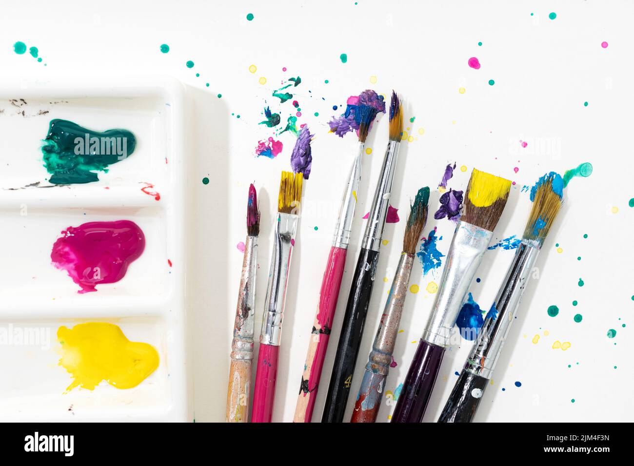 Art Paint brushes, palette and colorful splatter on white canvas paper Stock Photo