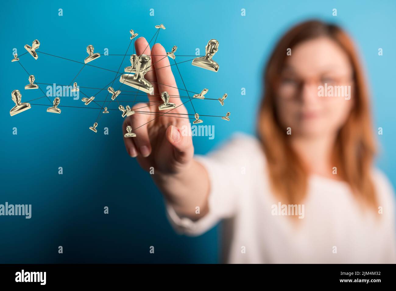 A woman pointing at a 3D rendering of profile icons floating in the air ...