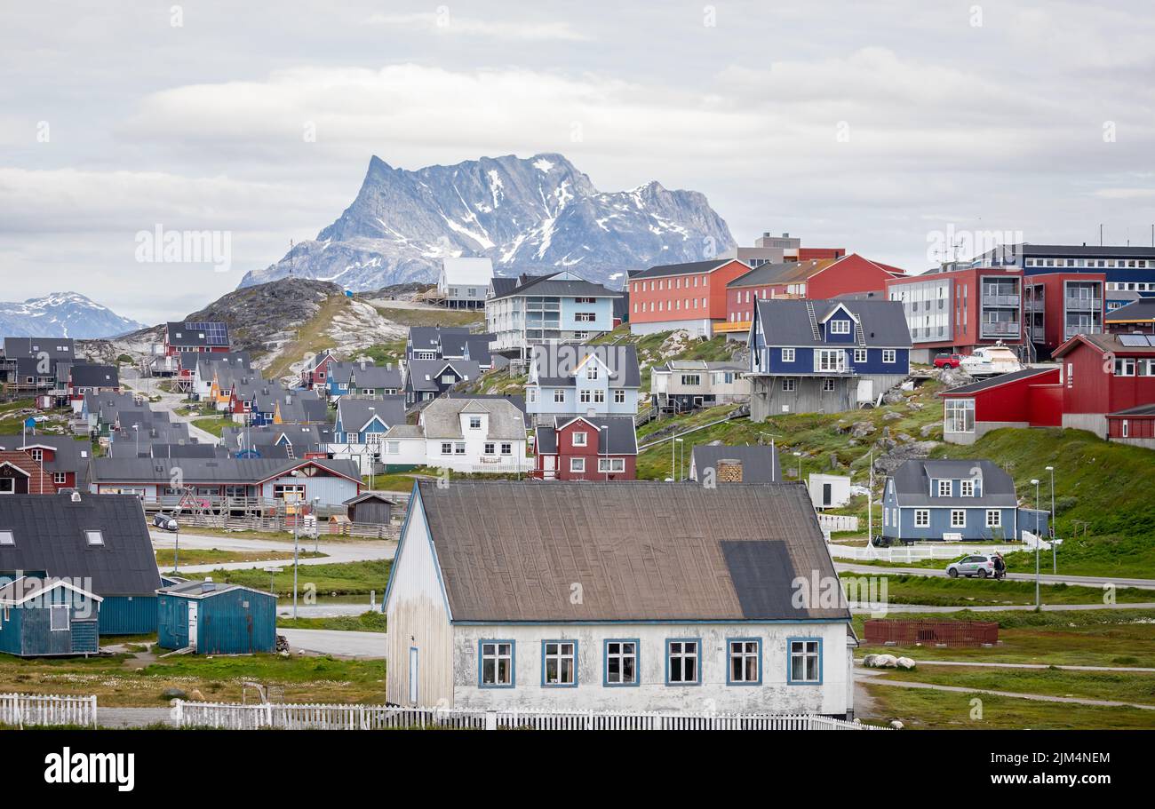 Multi coloured houses set against a snow covered mountain backdrop in Nuuk, Greenland on 20 July 2022 Stock Photo